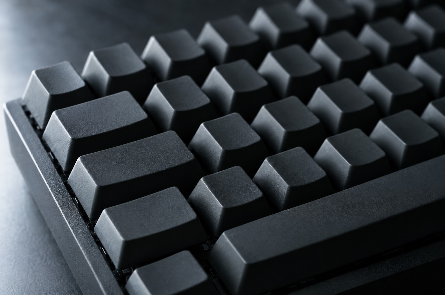 Unlabelled dark keycaps on a keyboard, seen at a low angle